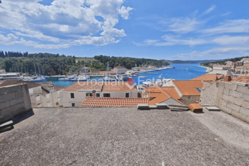 A bare shell house for sale on Brac, Croatia, and a view of a coastal town with houses, the sea, boats, and vegetation.