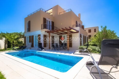 A villa for sale on Brac, Croatia, with terraces and a terrace on the ground floor with a pool and sun loungers.
