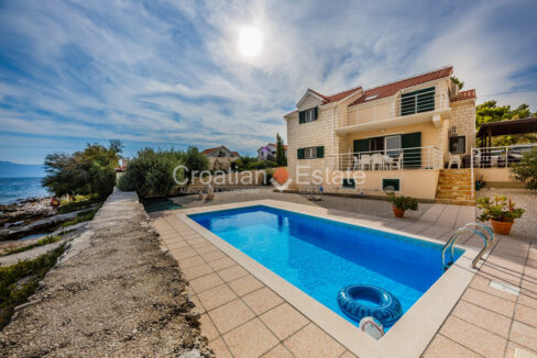 A seafront villa for sale on Brac, Croatia, with a balcony, a terrace with outdoor furniture, and a terrace with a pool.