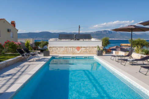 A terrace with pool of a luxury house for sale on Ciovo, Croatia, overlooking the sea and hills.