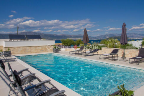 A terrace with a pool, sun loungers, sun umprellas