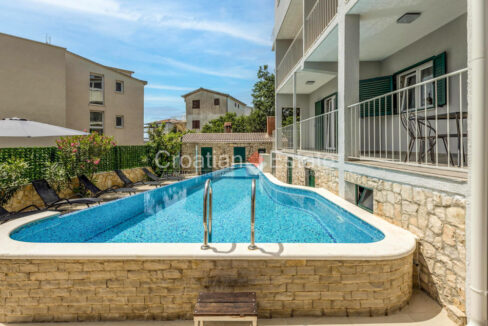 A house for sale on Ciovo, Croatia, with terraces and a patio with a pool and sun loungers.
