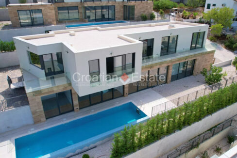 A villa for sale on Ciovo, Croatia, with many glass walls and a terrace with a pool.