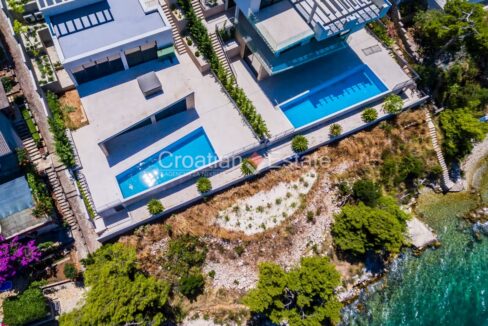 A seafront villa for sale on Ciovo, Croatia, with terraces, a pool, stairs, and garden sections with plants.