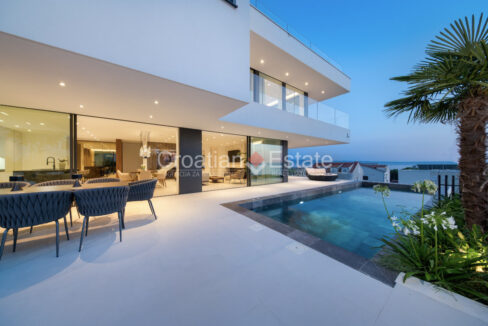 A villa for sale in Podstrana, Croatia, with a terrace, a balcony, and a terrace with a dining area, a pool, and plants.