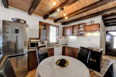 An apartment for sale in Trogir, Croatia, with a wooden ceiling and a dining room with a vintage kitchen.
