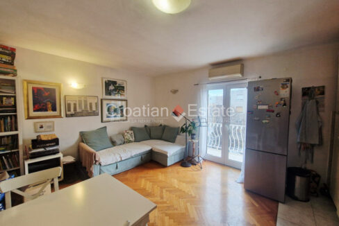 A flat for sale in Bacvice, Split, Croatia, with a living room with a dining table, a sofa, and a refrigerator.