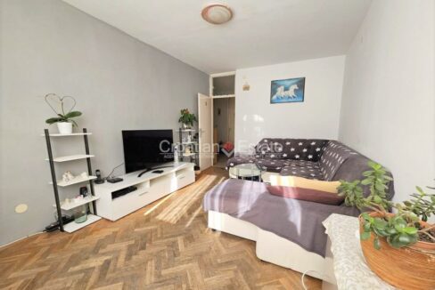 An apartment for sale in Brda, Split, Croatia, with a living room with a TV set on a TV bench, a sofa, and other furniture.