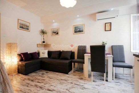 An apartment for sale in Split, Croatia, with an open-concept living room with a sofa, a dining area, and an air conditioner.