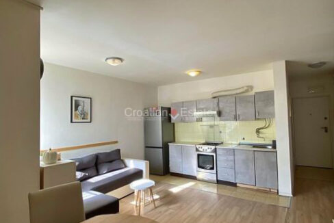 An apartment for sale in Sucidar, Split, Croatia, with a furnished, open-concept living room with a kitchen, and a hall.