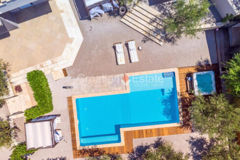 A villa for sale near Split, Croatia, with a patio with a pool, a jacuzzi, canopies, plants, and sun loungers.