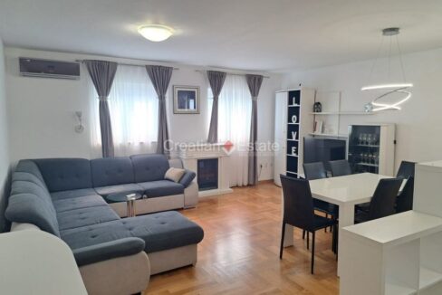 An apartment for sale in Znjan, Split, Croatia, with an open-concept living room with a dining area, a fireplace, and an air conditioner.