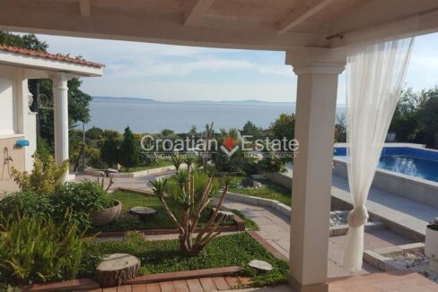 A house for sale in Split, Croatia, with a partially covered terrace with a pool, walkways, garden parts, and a sea view.