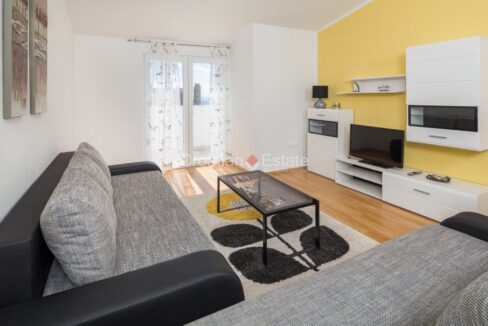 An apartment for sale in Strozanac, Croatia, with a sofa, a coffee table, a TV set, and a loggia.