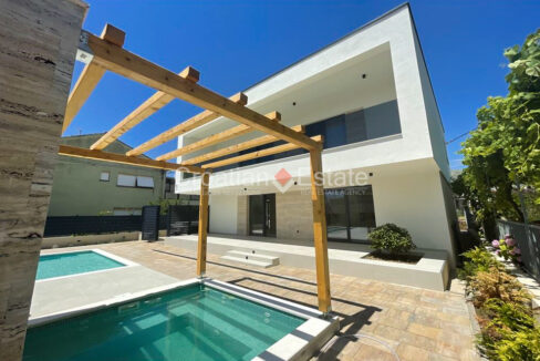 A villa for sale in Trogir, Croatia, with a balcony and a terrace with a jacuzzi, a pergola, and a pool.